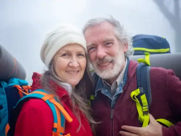 A smiling senior couple with backpacks on an outdoor adventure
