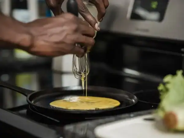 Home cook pouring whisked eggs into a cast-iron skillet