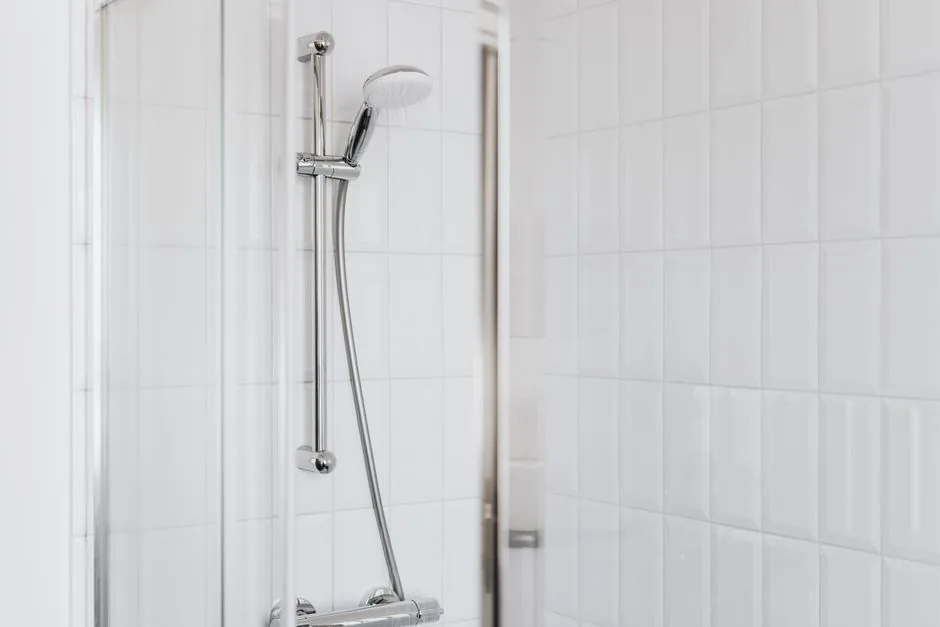 A clean white tiled shower in a bathroom