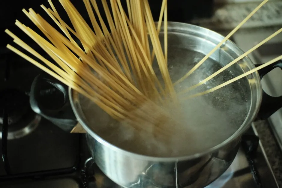 Spaghetti going into a pot of boiling water