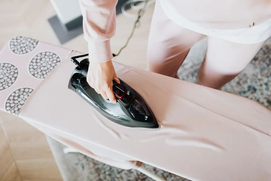 Pressing clothes with an iron on an ironing board
