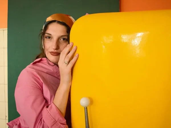 A woman in a headscarf beside a retro yellow refrigerator