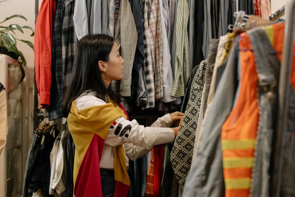 A woman browsing a rack of secondhand clothes at a thrift store