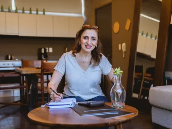 An older woman planning and writing in a notebook at her kitchen table