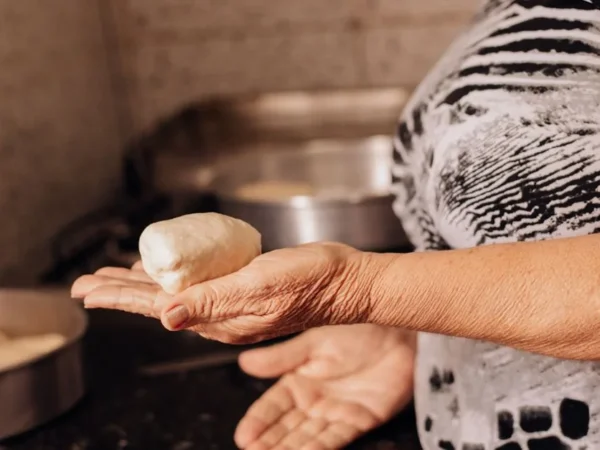 An older woman's hands shaping dough in her kitchen