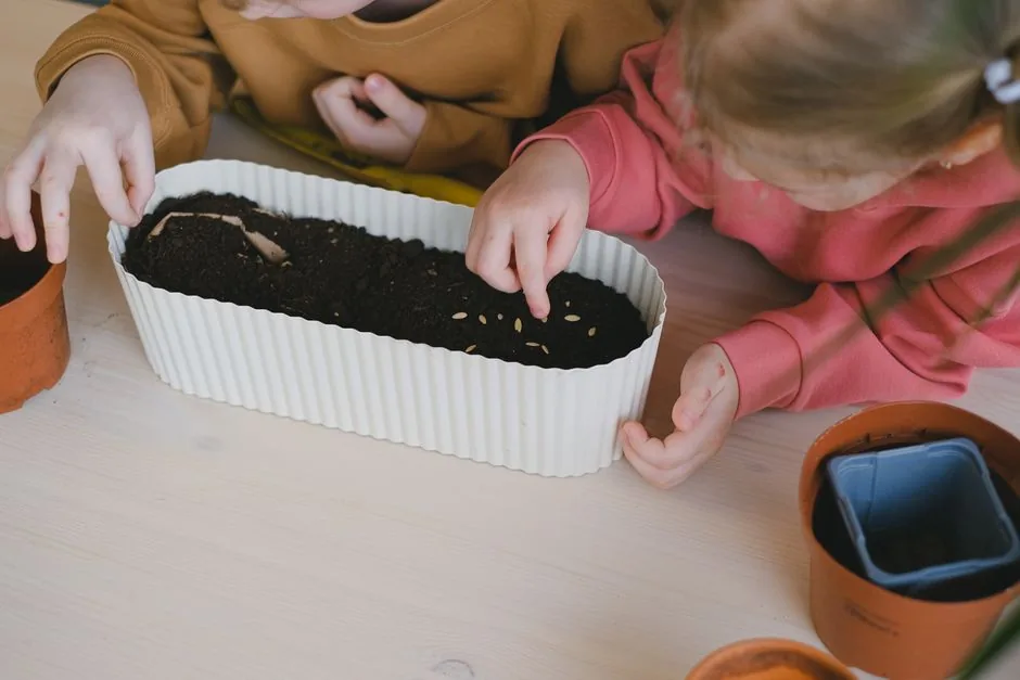 Children pressing seeds into a planter full of soil