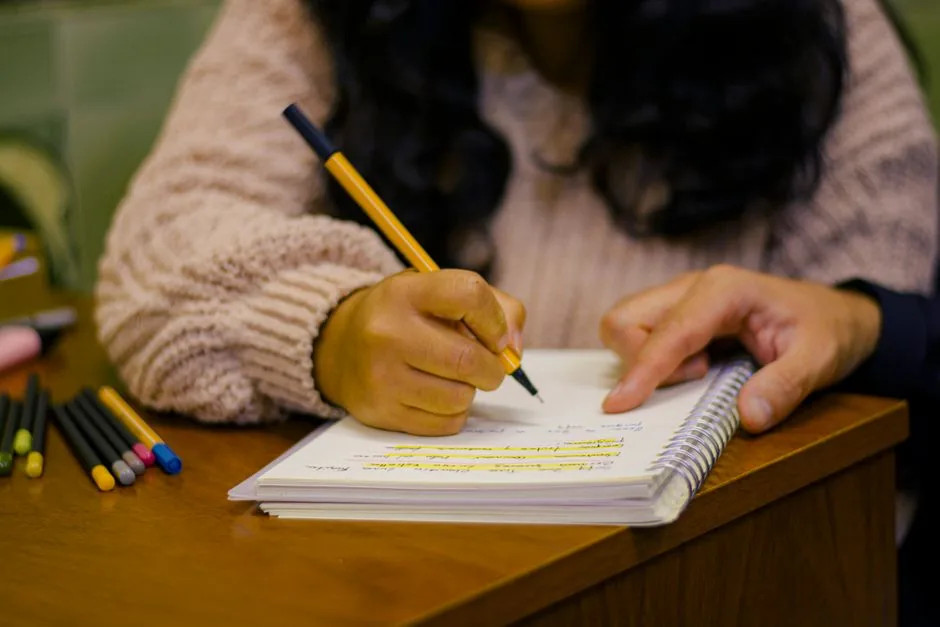 A hand writing with a pen in a paper notebook