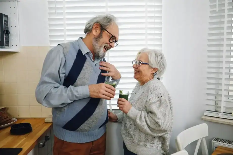 An older couple laughing together in their kitchen