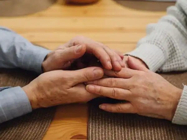 An elderly couple holding hands together across a table