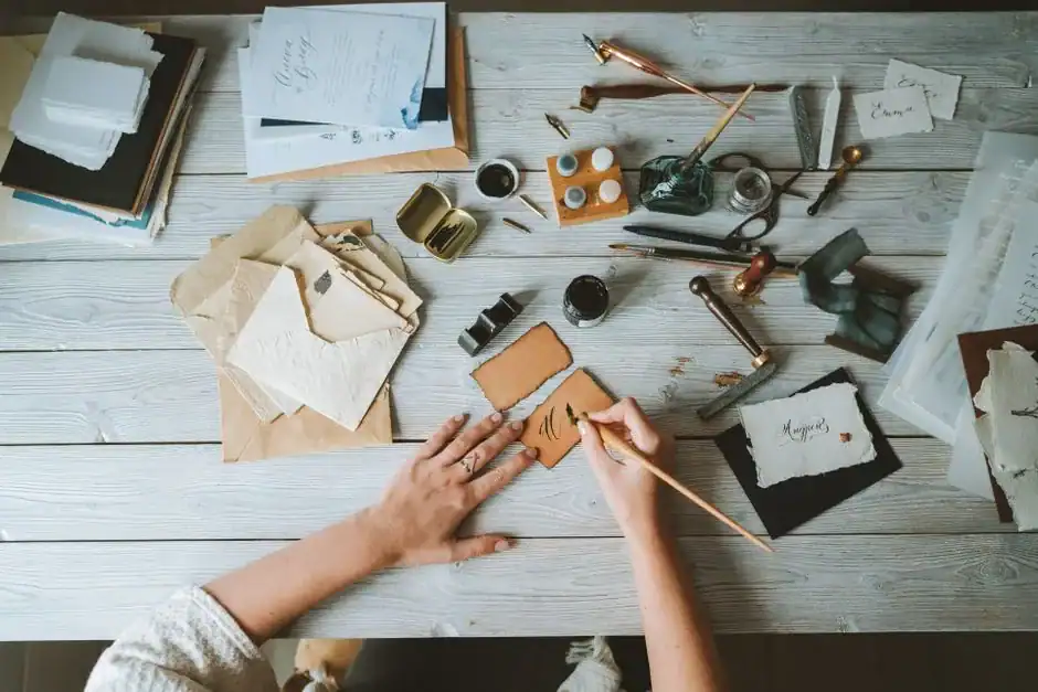 Hands writing a note by hand at a wooden desk