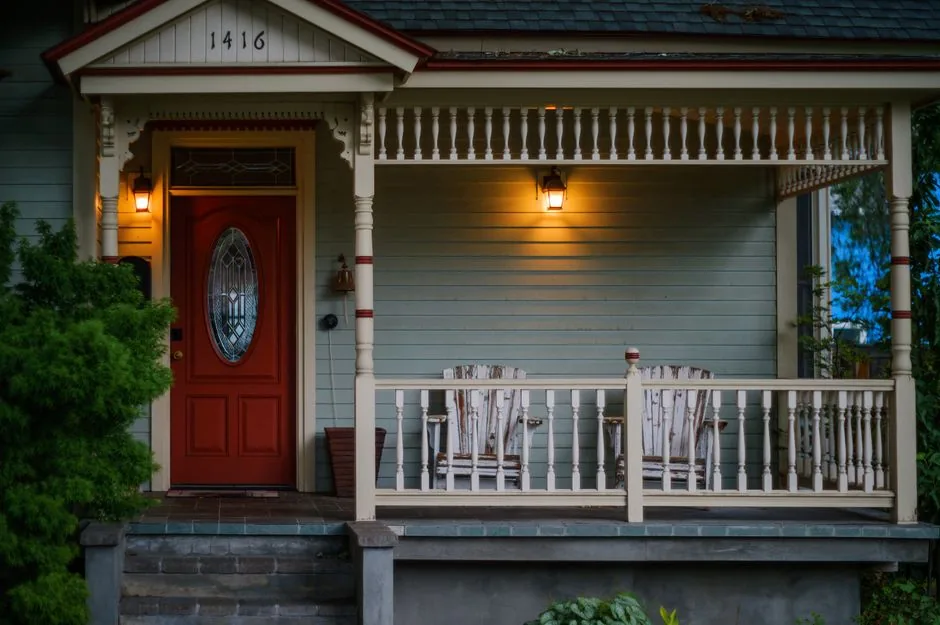 A classic front porch with rocking chairs and a red door