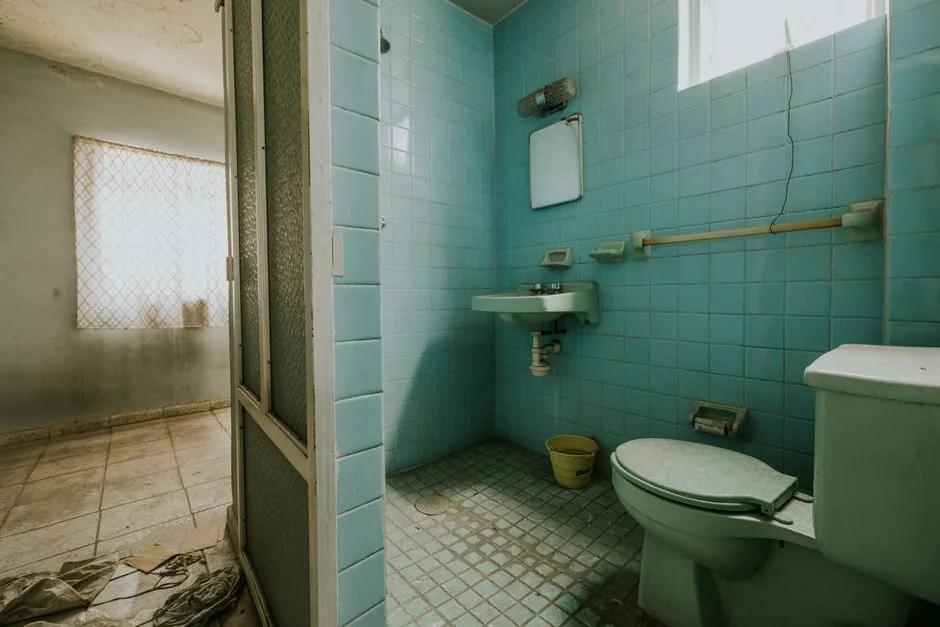 A retro bathroom tiled in turquoise with a matching toilet
