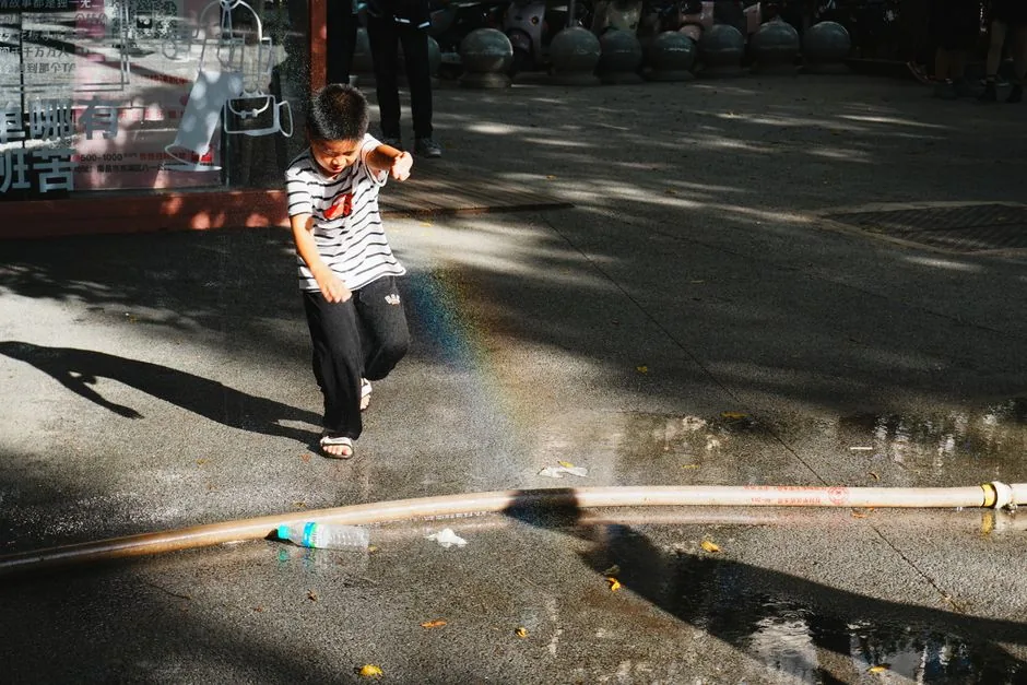 A child running through a spray of water on a hot day