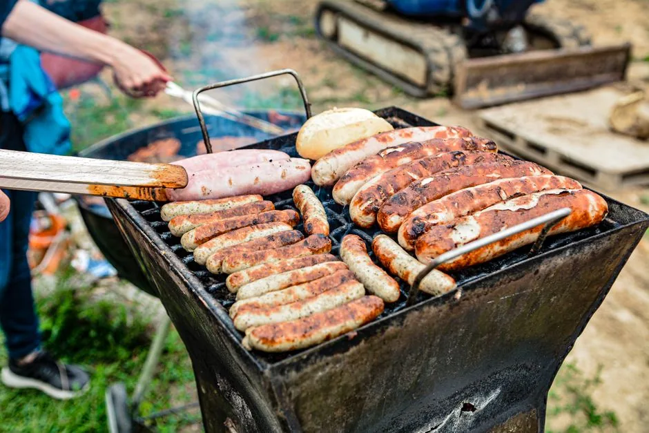 Sausages and rolls cooking on a backyard grill