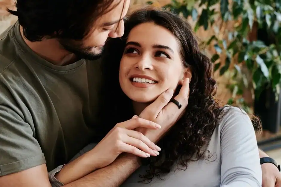 Loving couple embracing in a warm, cozy indoor setting with greenery, symbolizing affection and connection.