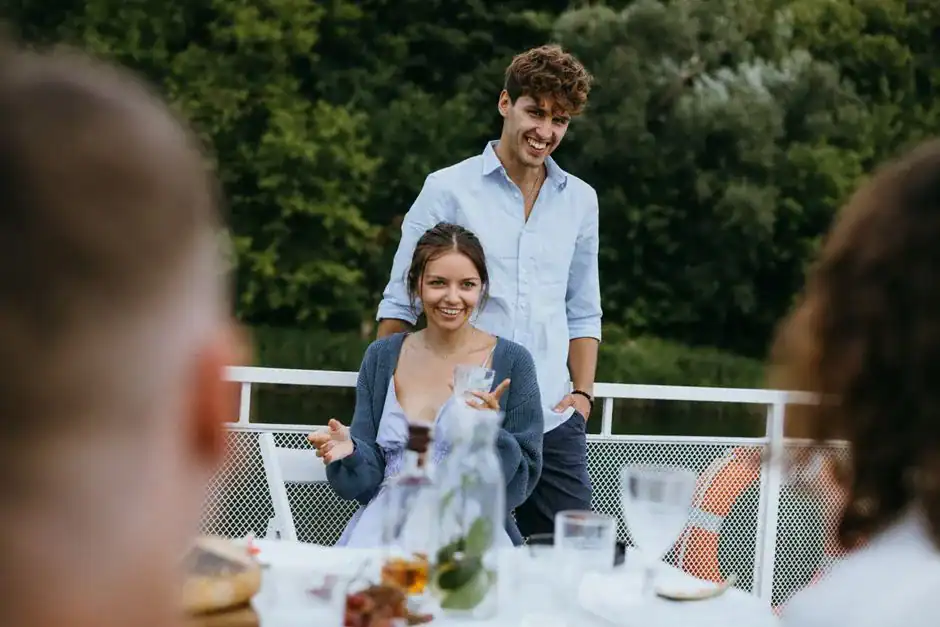 Cheerful young couple at an outdoor dinner with friends, enjoying lively conversation and good company.