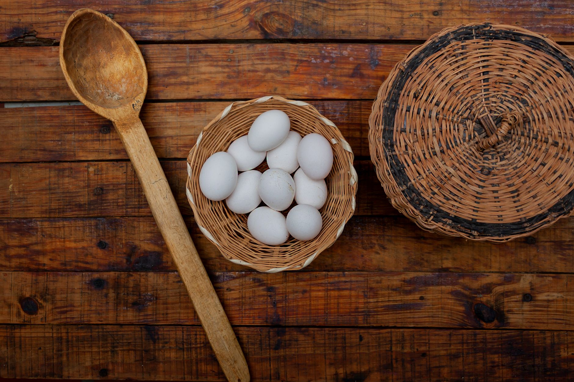 Fresh eggs in a woven basket on a rustic wooden table