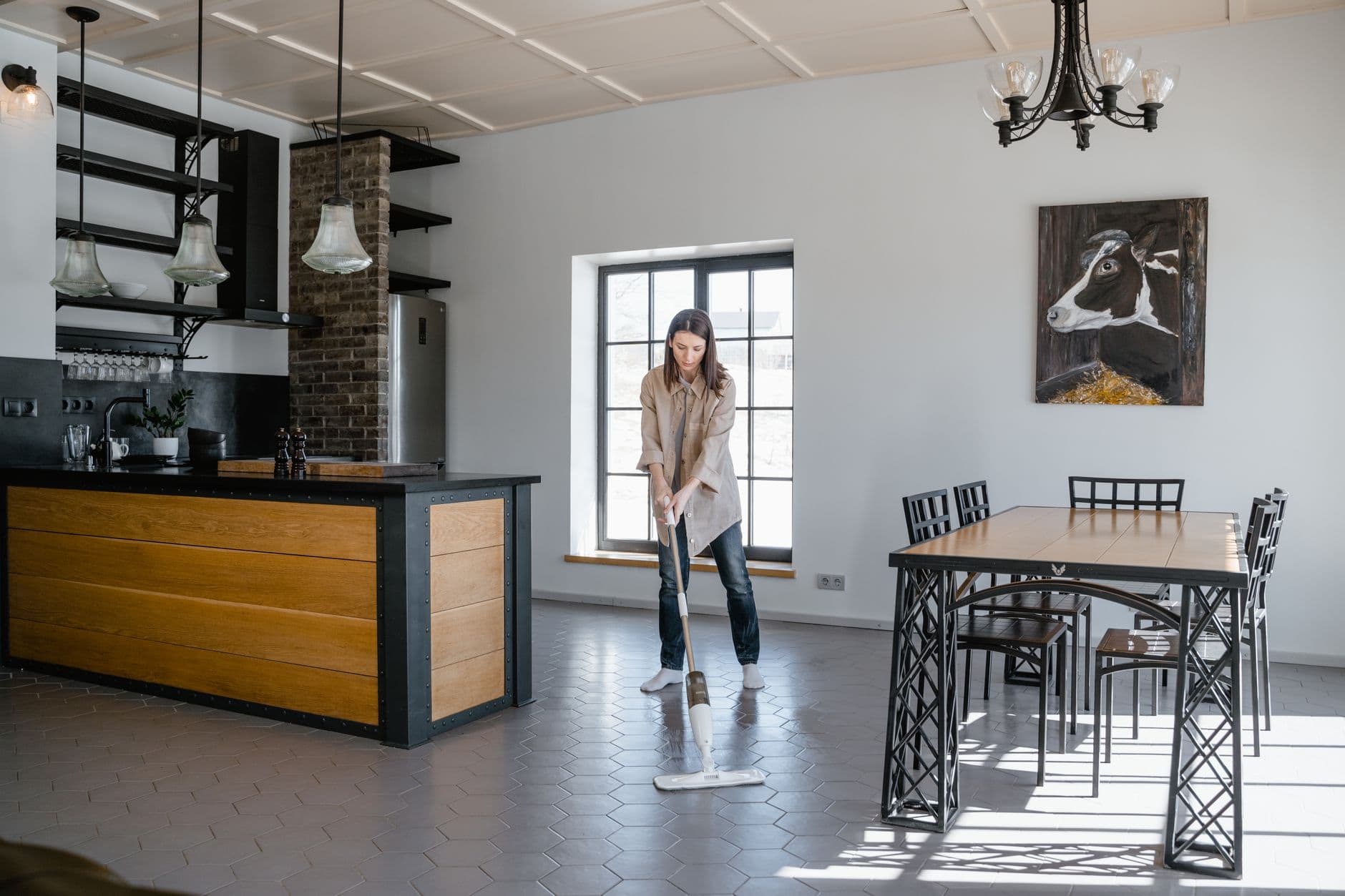 Woman mopping a sunlit kitchen and dining room floor