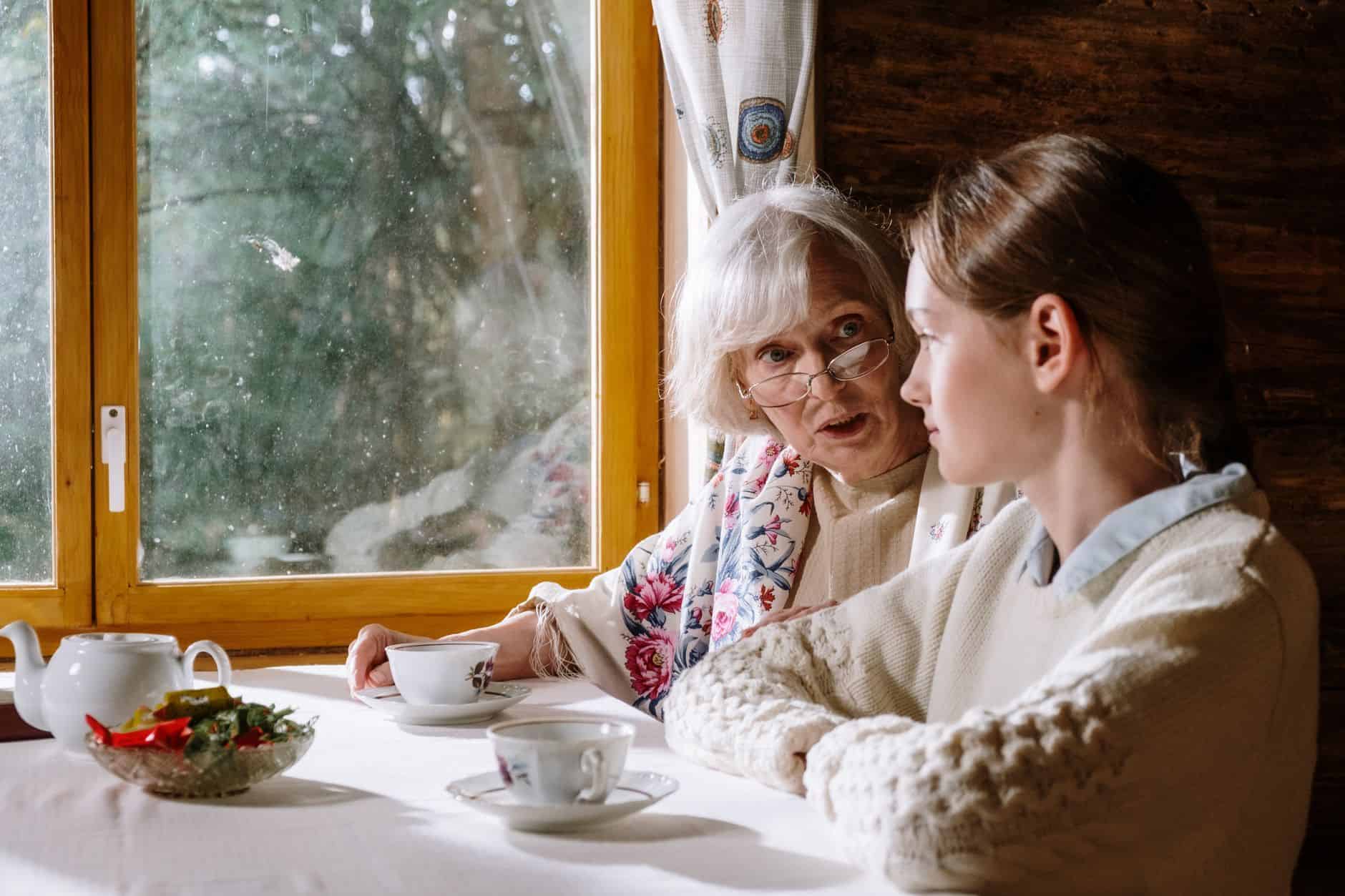 Grandmother and granddaughter sharing tea and conversation by a window