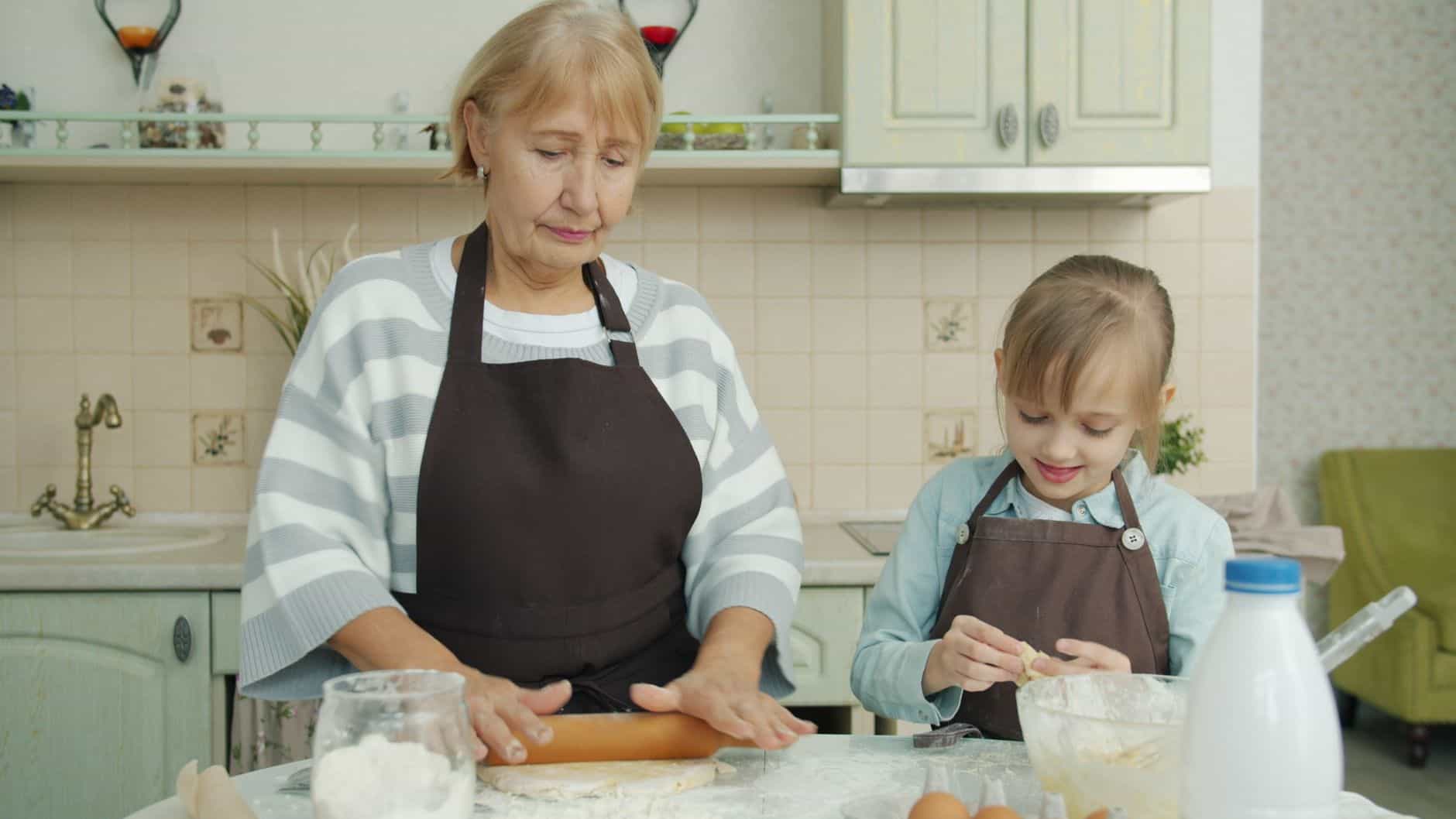 Grandmother and granddaughter baking together at the kitchen counter