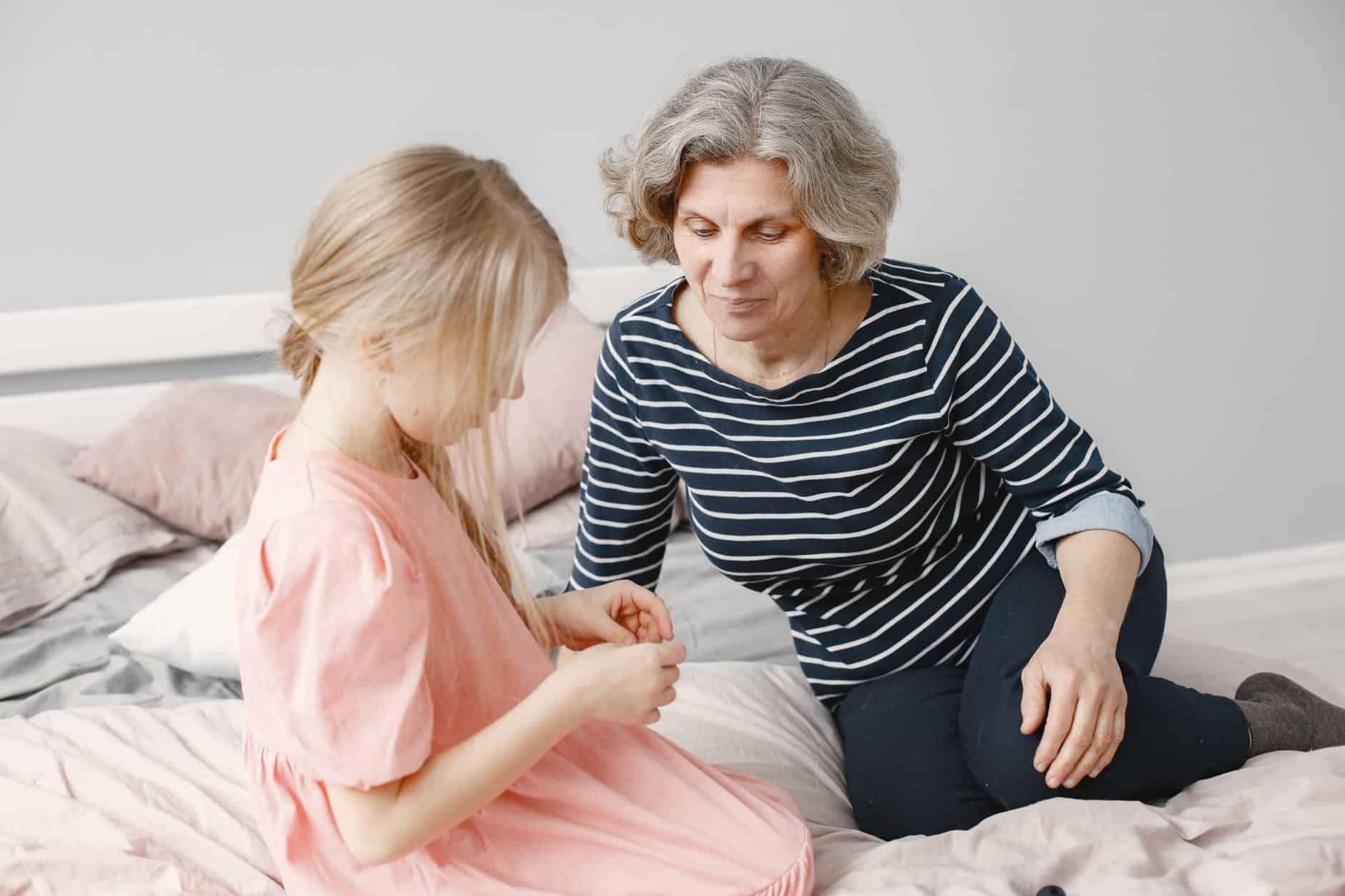 Grandmother sitting on the bed talking with her granddaughter