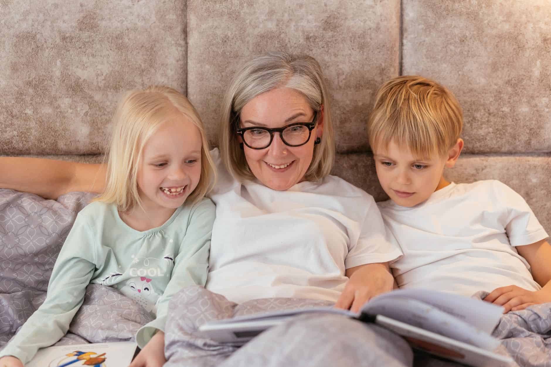 Grandmother reading in bed with her grandchildren