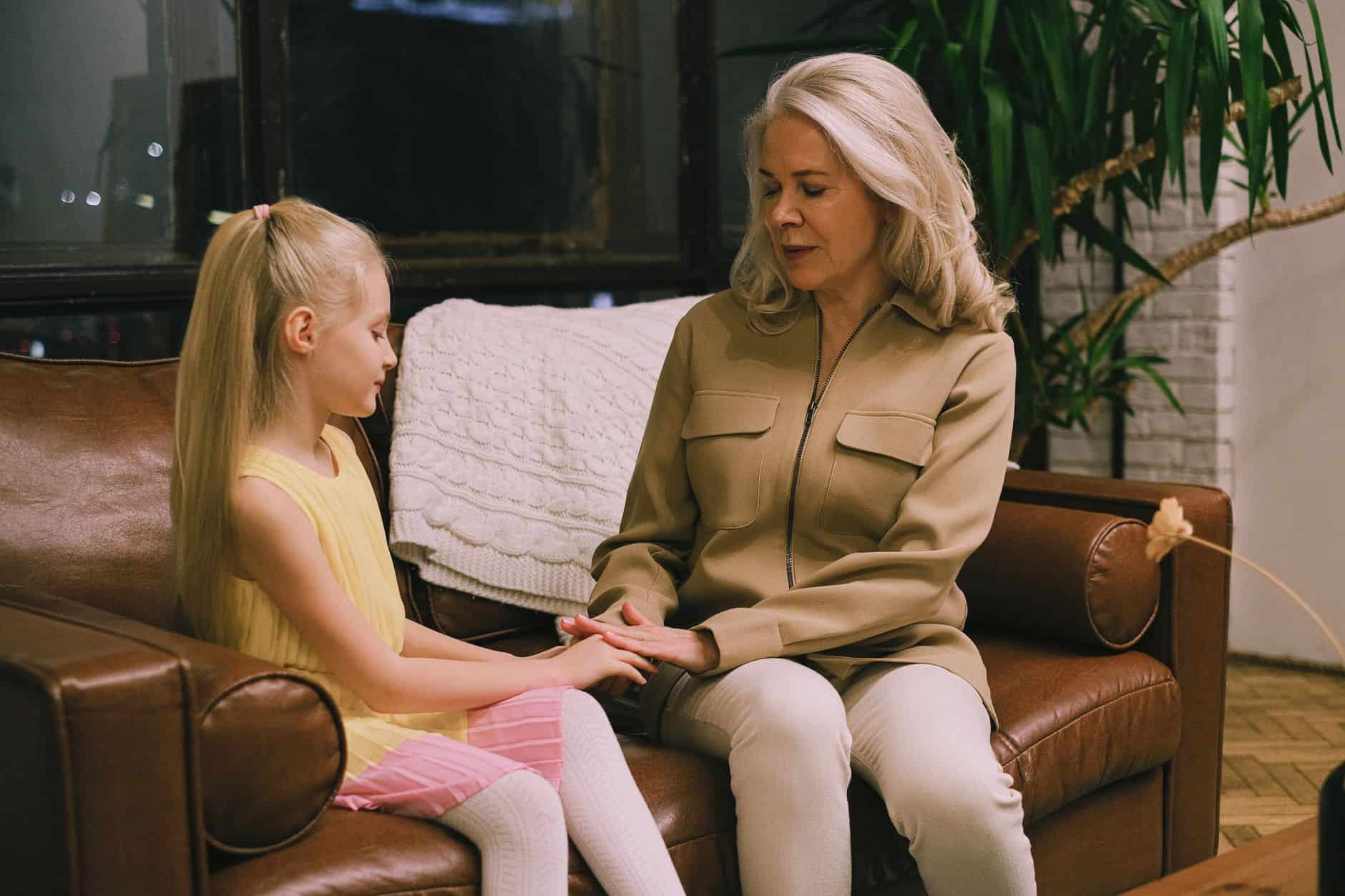 Grandmother sitting on the sofa talking with her granddaughter