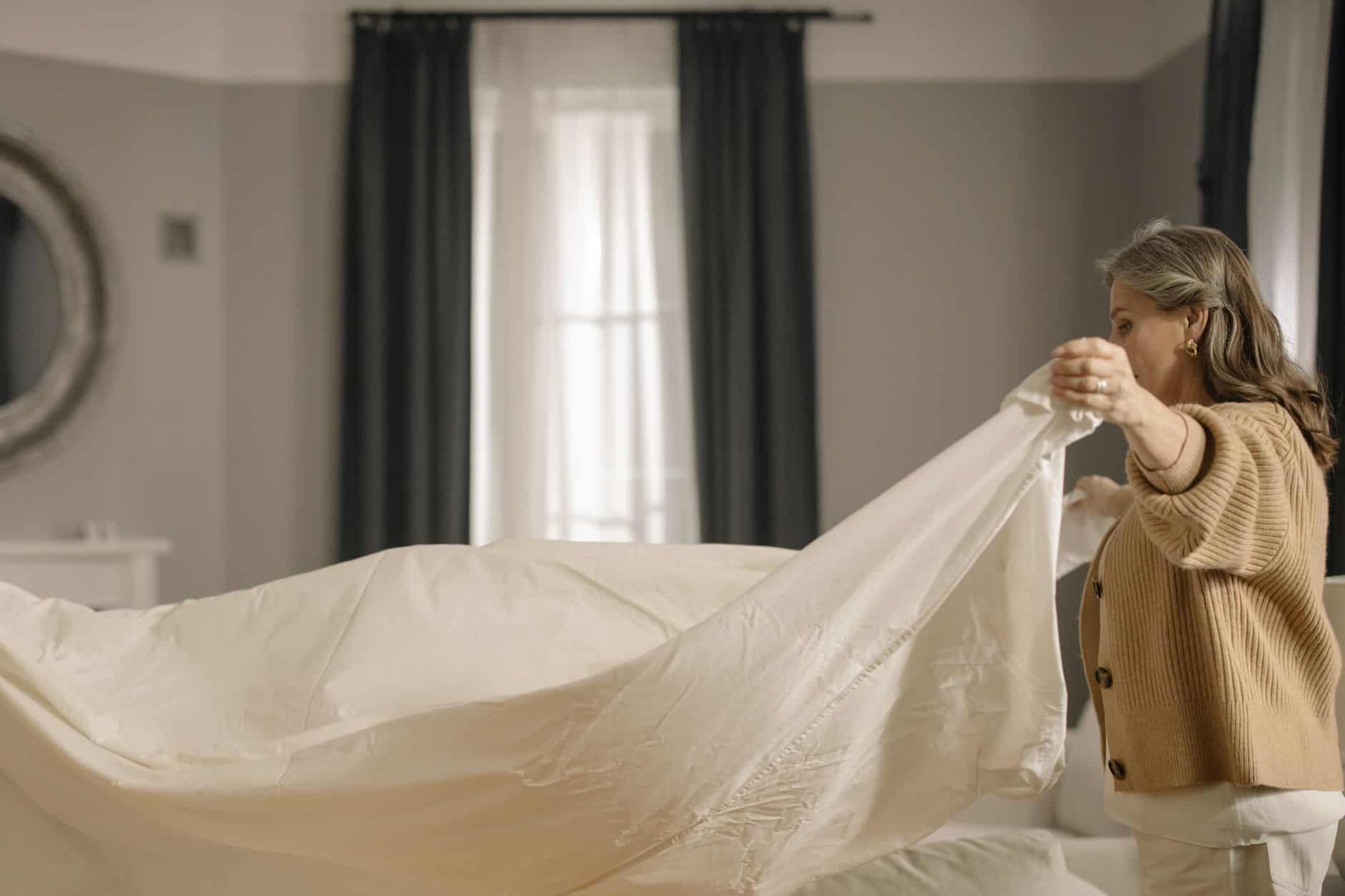 Grandmother making her bed neatly in a tidy bedroom