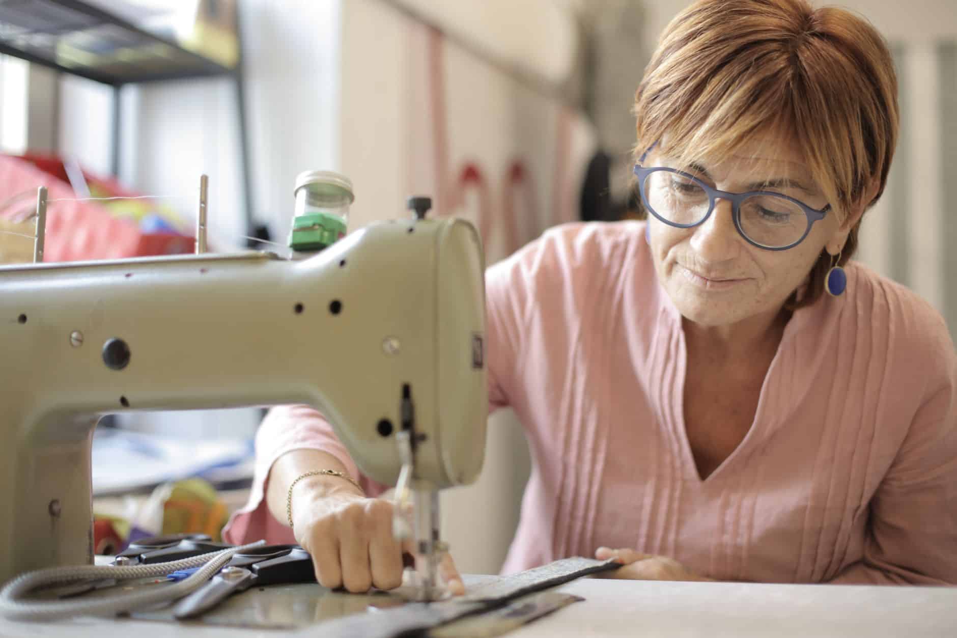 Grandmother sewing at a vintage sewing machine in a bright room