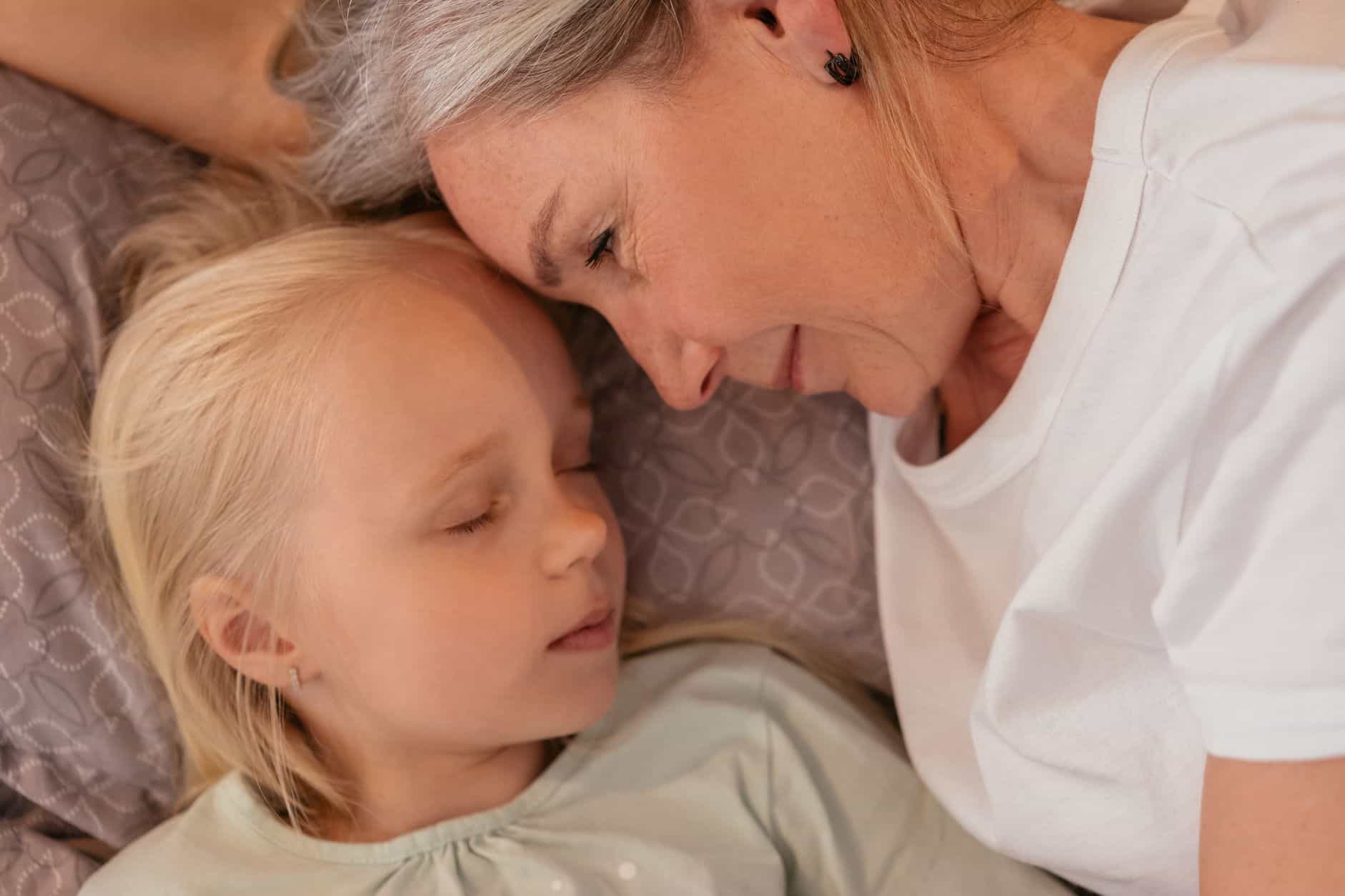 Grandmother lying close with her granddaughter at bedtime