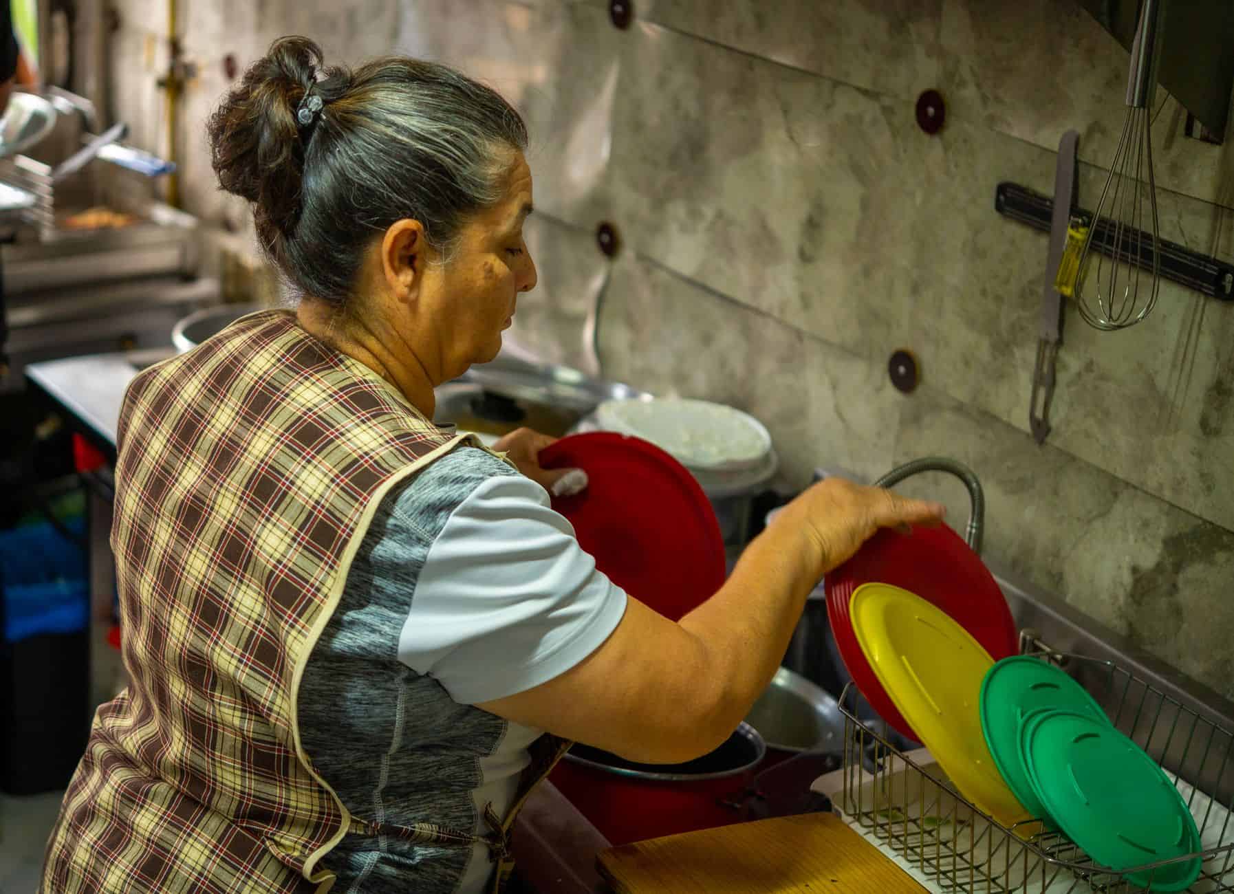 Grandmother washing dishes at the kitchen sink