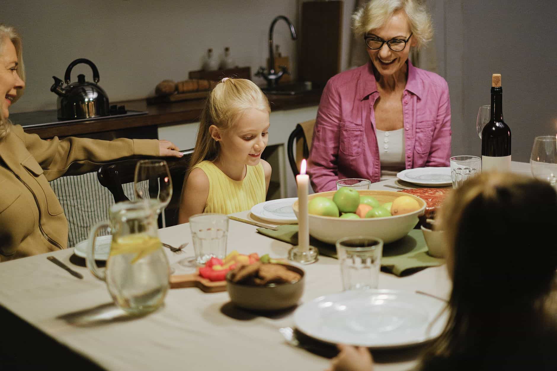 Grandmother eating dinner with her family at the kitchen table