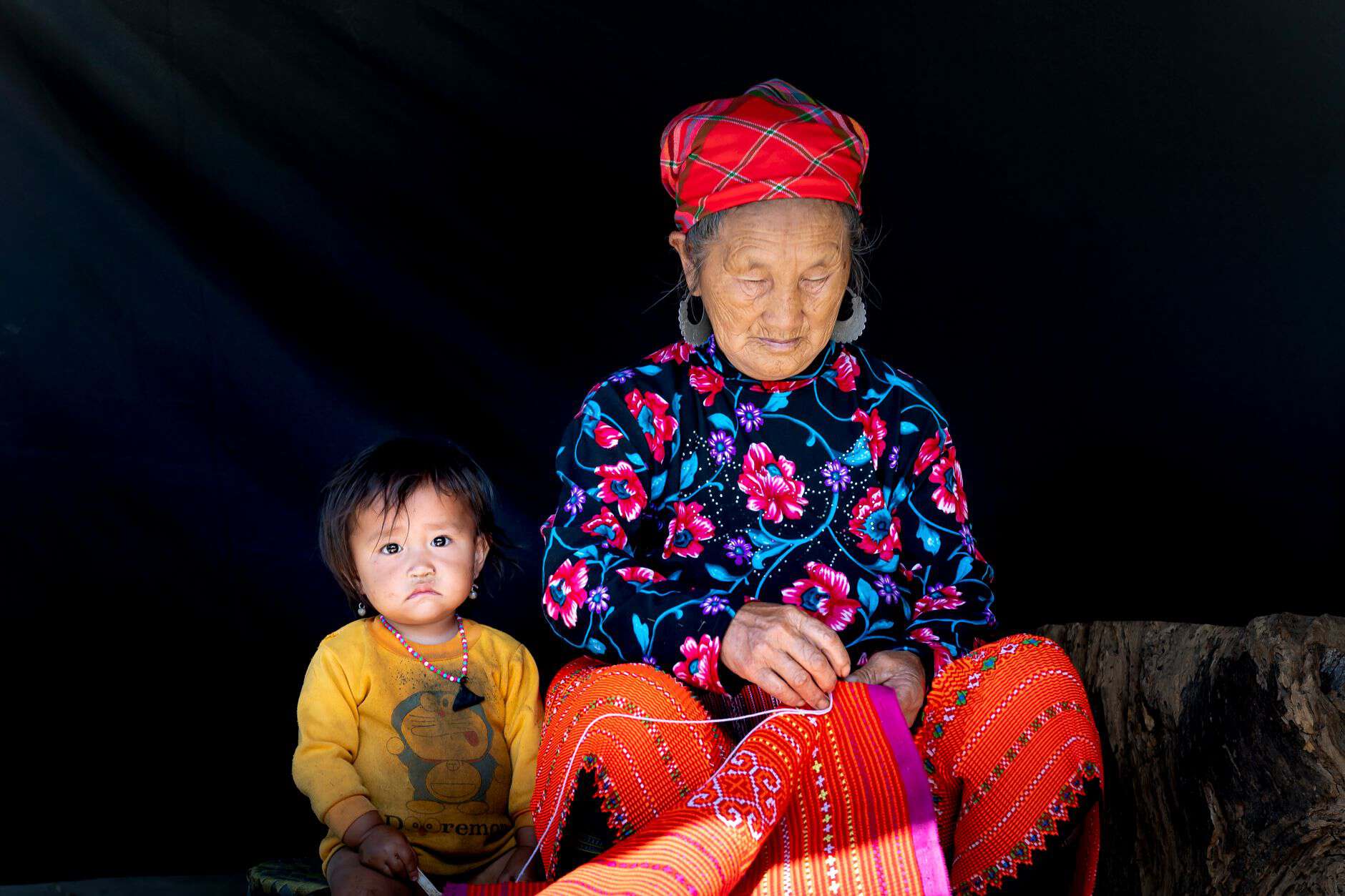 Grandmother sewing beside a small child