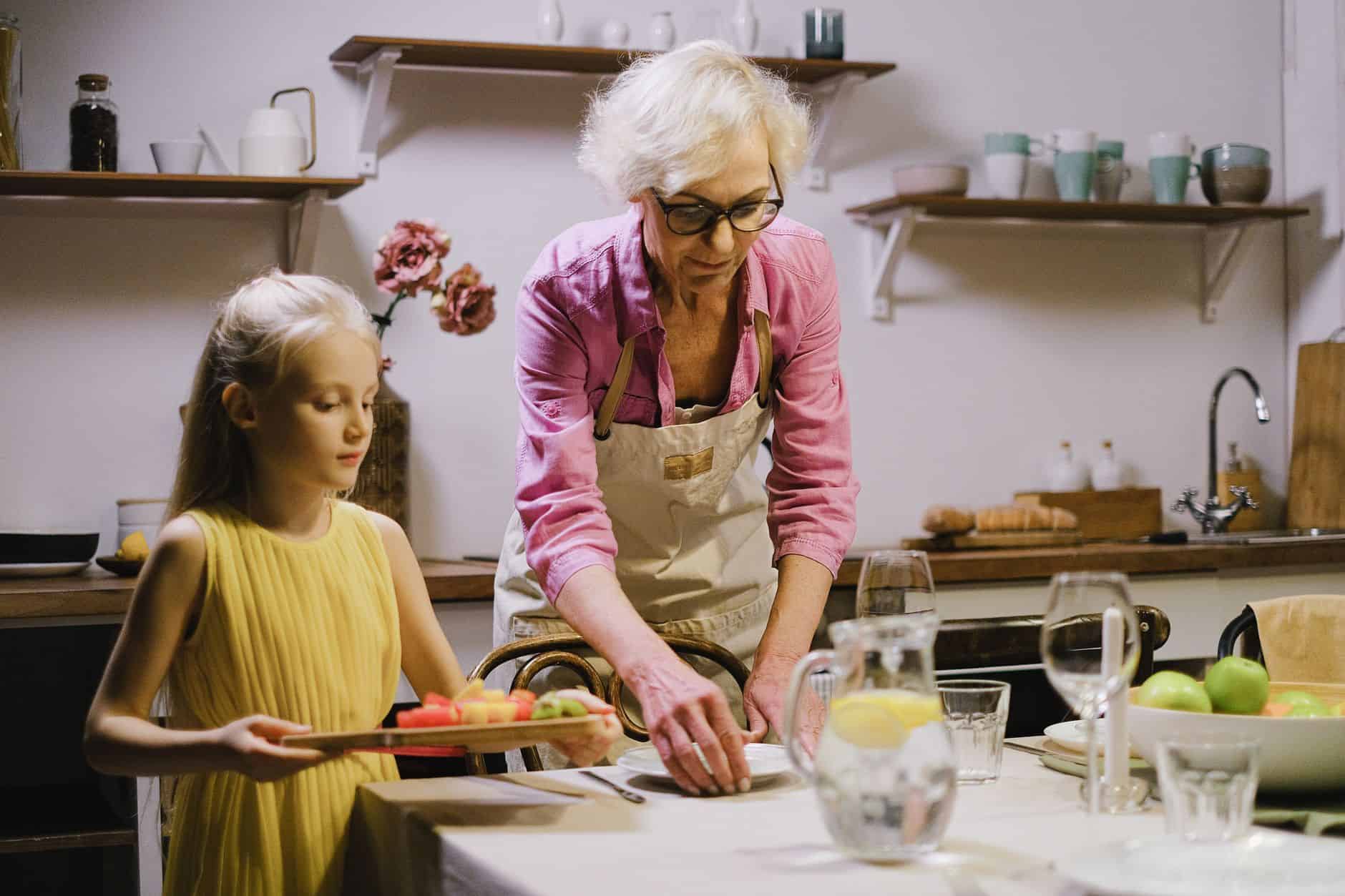 Grandmother and granddaughter setting the kitchen table together