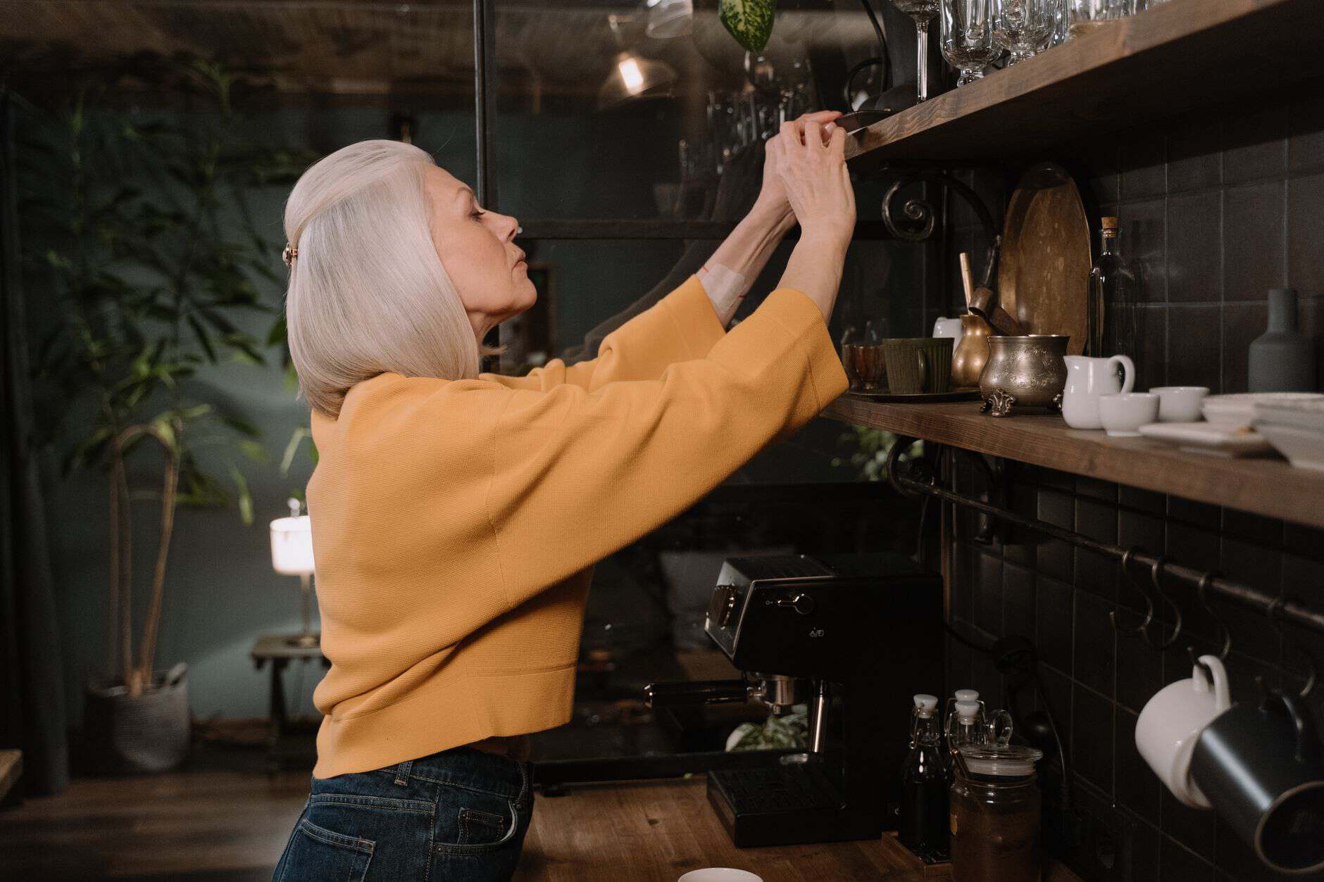 Grandmother putting dishes away on a kitchen shelf